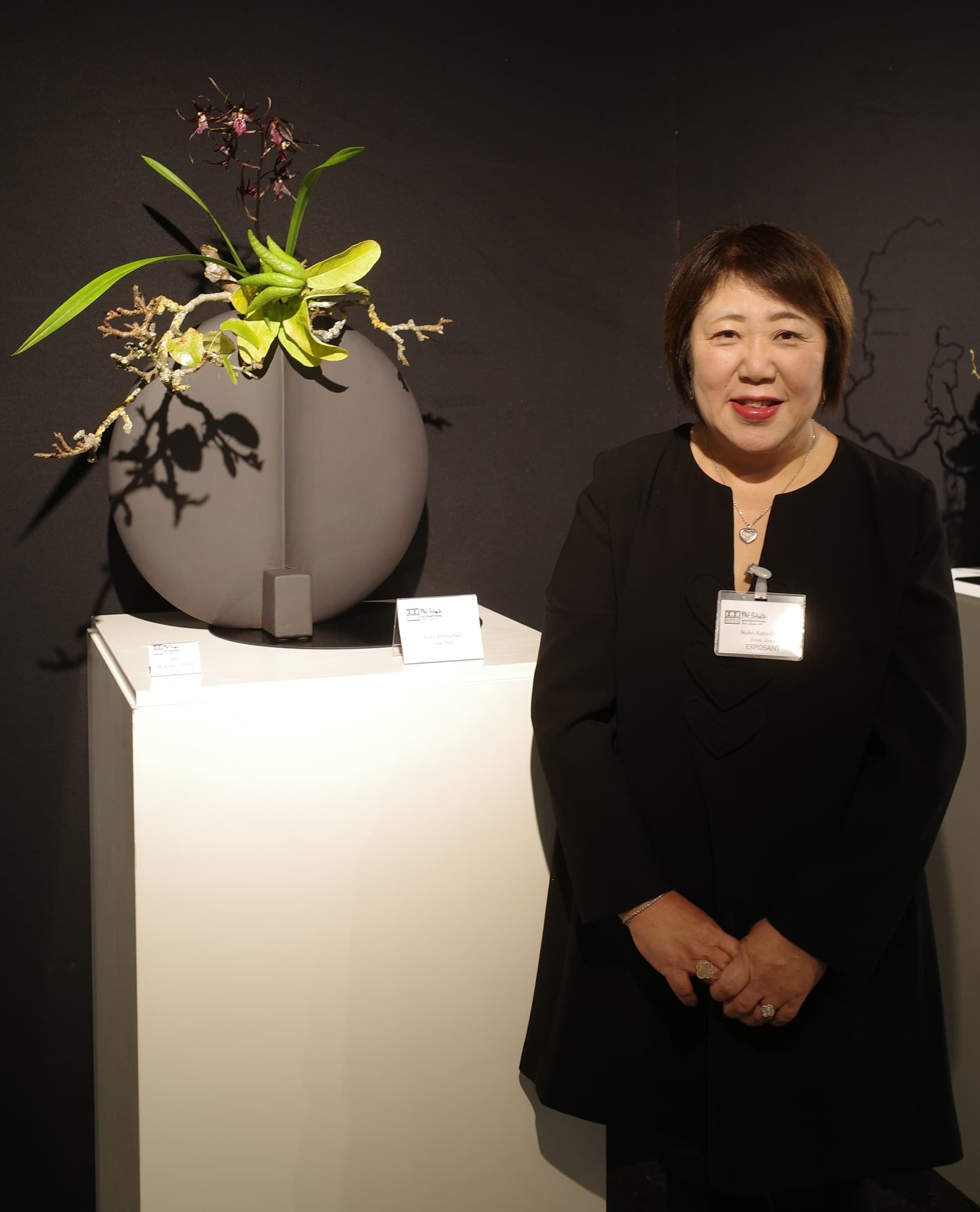 Portrait d'Ikuko Kato aux côtés d'une composition d'ikebana